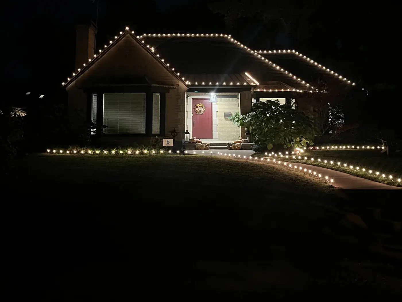 Warm white C9 roofline lights with a stake-lit front walkway on a DFW home