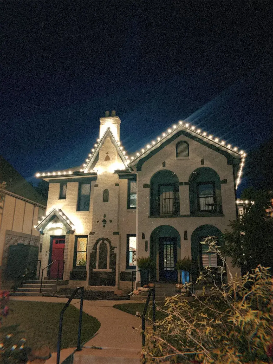 C9 Christmas lights outlining the peaks and chimney of a Tudor-style DFW home
