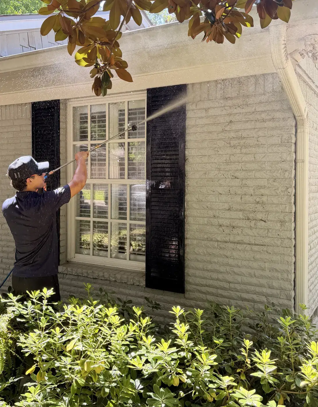Pristine crew member soft washing the painted brick exterior and eaves of a DFW home