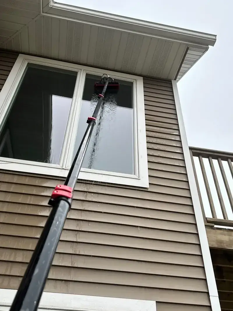 Water-fed pole washing a second-story window on a DFW home